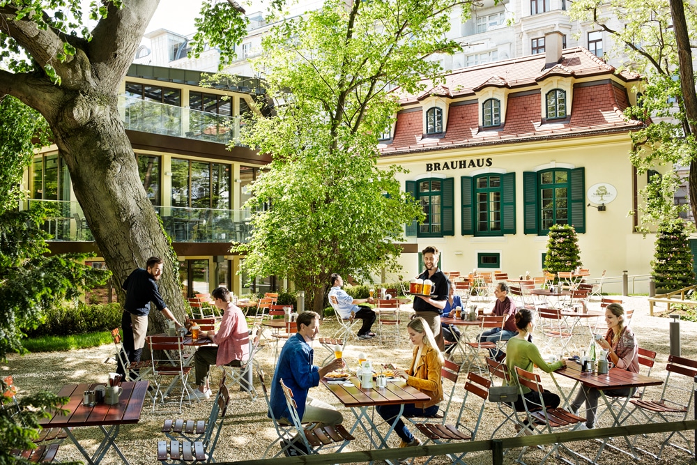 Gastgarten mit historischem Gebäude und Brauerei. © Stöckl im Park